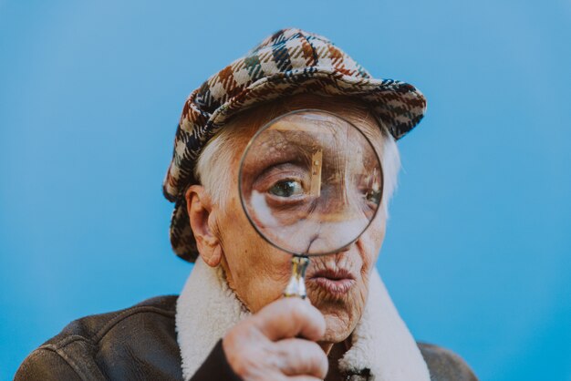 Photo portraits drôles avec la vieille grand-mère. haute femme agissant comme enquêteur avec la lentille grossissante