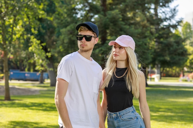 Portraits de jeune couple debout dans le parc et regardant de côté