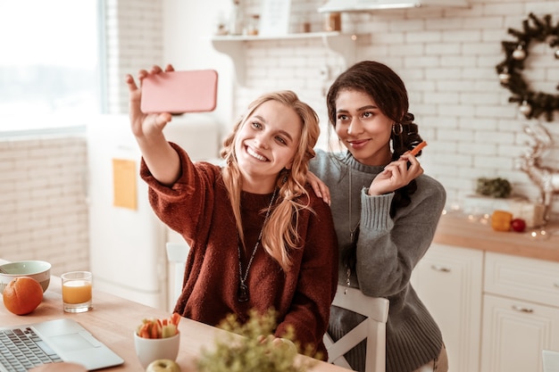 Posant pour la photo. Des filles coquettes attrayantes sont extrêmement mignonnes tout en photographiant pour un selfie personnel