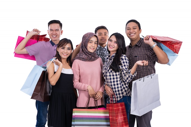 Pose d'amis de groupe portant des sacs à provisions ensemble