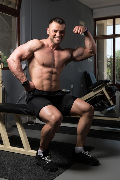 Pose de biceps d'un jeune homme en salle de sport