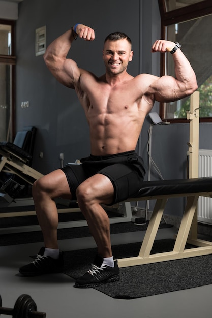 Pose de biceps d'un jeune homme en salle de sport