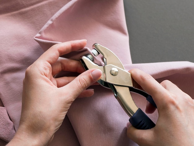 Photo pose d'un bouton pression en tissu éponge rose à l'aide d'un rivet perforant