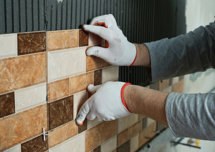 Pose de carreaux de céramique. Carreleur plaçant le carrelage mural en céramique en position sur l'adhésif