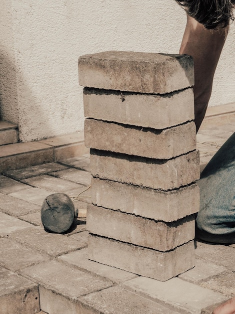 Pose de dalles de pavage en béton gris dans le patio de l'allée de la cour de la maison Ouvrier professionnel maçon trottoir ou patio sur une base de fondation en sable nivelée