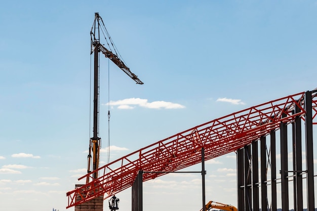 Pose de fermes métalliques et de charpente lors de la construction d'un bâtiment industriel ou d'une usine Le travail des installateurs lors de la pose de la toiture Construction d'un grand atelier de charpente