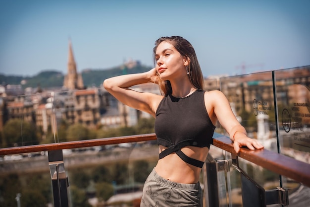 Pose d'une jeune femme sur la terrasse d'un hôtel regardant la ville d'en haut