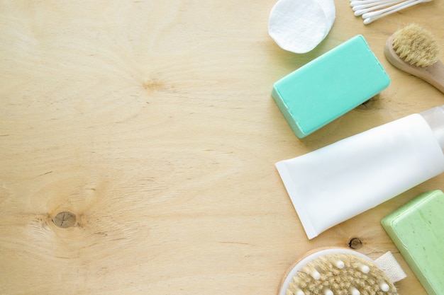 Pose à plat de produits de bain et d'hygiène. Savon, shampoing et brosses de massage sur fond en bois, copyspace.