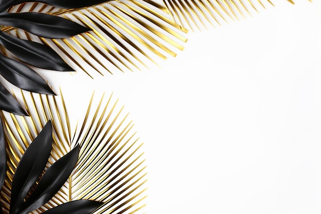 Pose plate dorée et noire avec branches de feuilles de palmier tropicales