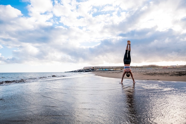 position équilibrée dure pour femme forte et sportive à la plage sur le rivage