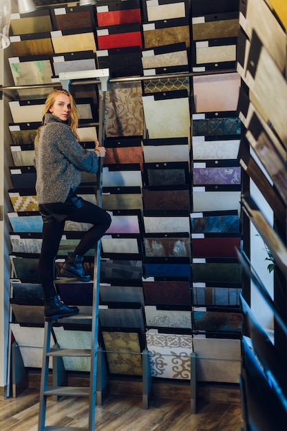 positive jeune femme choisit avec de la peinture pour la maison de réparation dans le magasin.