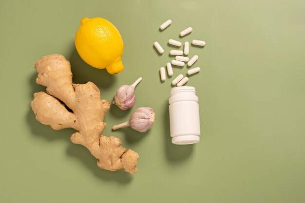 Pot d'ail citron racine de gingembre frais avec des pilules de vitamines fond vert médecine alternative ayurveda