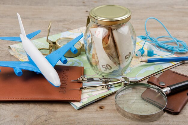 Photo pot avec de l'argent pour un passeport de cartes de voyage et d'autres trucs pour l'aventure sur la table