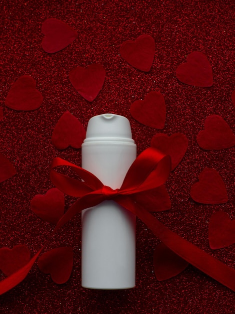 Photo pot blanc avec crème pour le visage est sur fond de papier coeur rouge