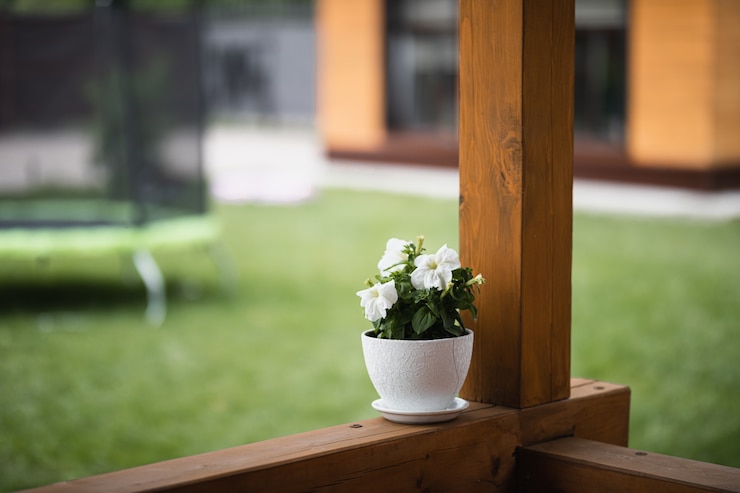 Photo un pot blanc avec une fleur maison se dresse sur la véranda