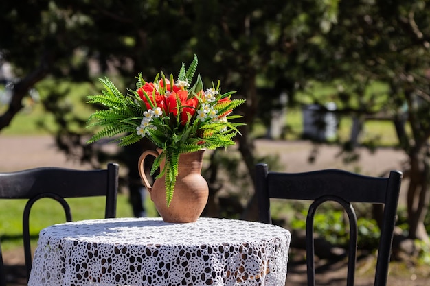 Un pot avec un bouquet de fleurs sur une table avec une nappe à l'extérieur