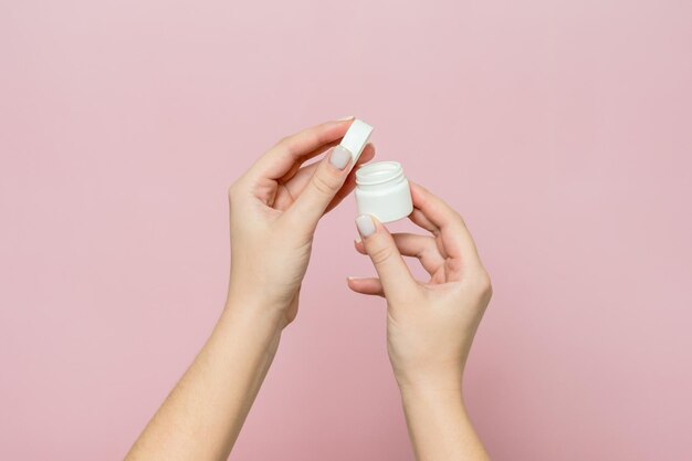 Pot ou bouteille blanc avec pommade crème dans les mains de la femme Bouteille de soin du visage avec produit cosmétique