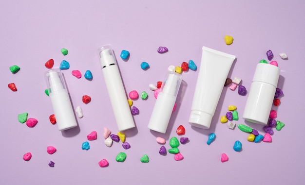 Pot, bouteille et tubes en plastique blancs vides pour cosmétiques sur fond violet. Emballage pour crème, gel, sérum, publicité et promotion de produit, maquette