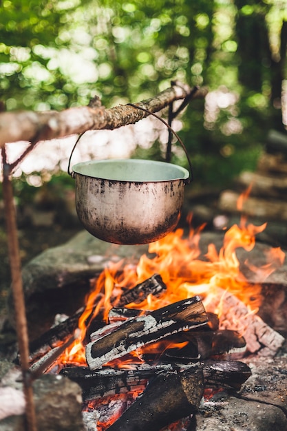 Le pot brûle près de la tente dans la forêt la nuit. Beau feu de camp dans un camp touristique à l'état sauvage.