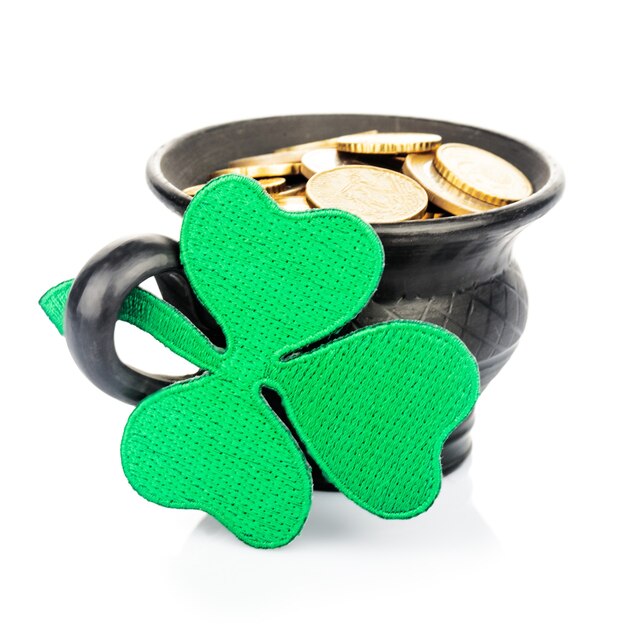 Pot en céramique noire avec pièces d'or et trèfle isolé sur blanc. Concept de la Saint-Patrick