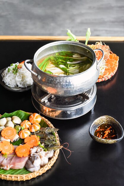 Pot chaud coréen avec des fruits de mer et des nouilles sur fond noir