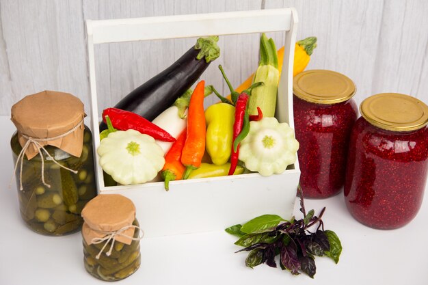 Un pot de concombres marinés et une récolte de légumes fraîchement récoltés. Aubergines et tomates au poivre