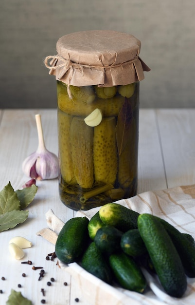 Un pot avec des concombres préparés pour le marinage et des ingrédients pour la marinade feuilles de raifort à l'ail et à l'aneth feuilles de cassis sur le fond d'une boîte avec des concombres en conserve prêts à l'emploi