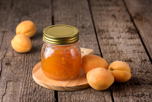 Pot de confiture d'abricot sur une planche à découper en bois cru fait maison l'horizontale d'abricot