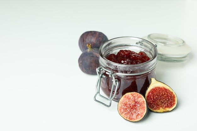 Pot avec confiture de figues et ingrédients sur fond blanc