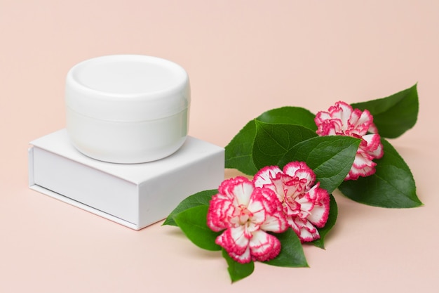 Pot de crème cosmétique blanc avec produit de soin sur rose clair