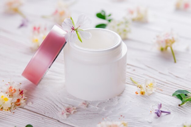 Pot à crème entouré de fleurs. Cosmétique bio