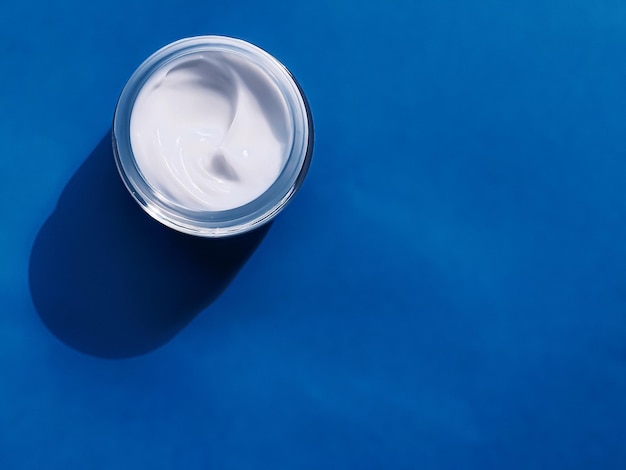 Pot de crème hydratante pour le visage comme échantillon de produit sur fond bleu beauté et soins de la peau science cosmétique