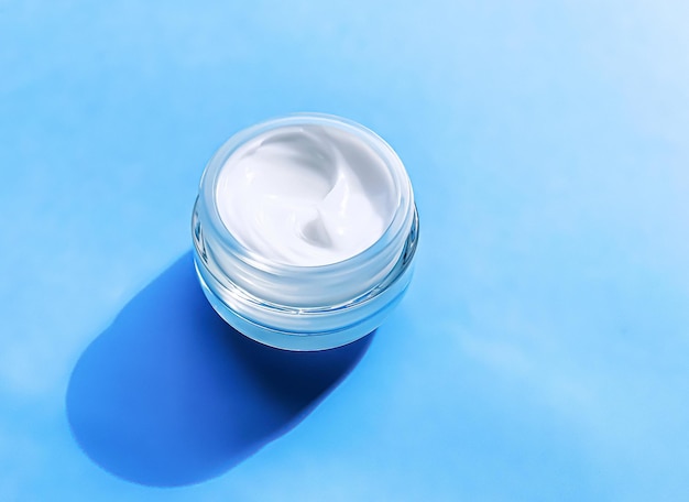 Pot de crème hydratante pour le visage comme échantillon de produit sur fond bleu beauté et soins de la peau science cosmétique