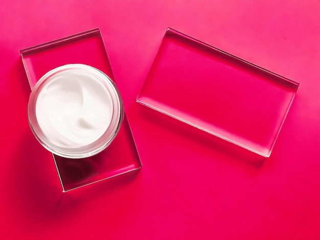 Pot de crème hydratante pour le visage sur verre et fond rose produit de beauté et science cosmétique de soin de la peau