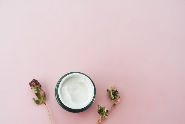 Pot de crème hydratante sur une table rose