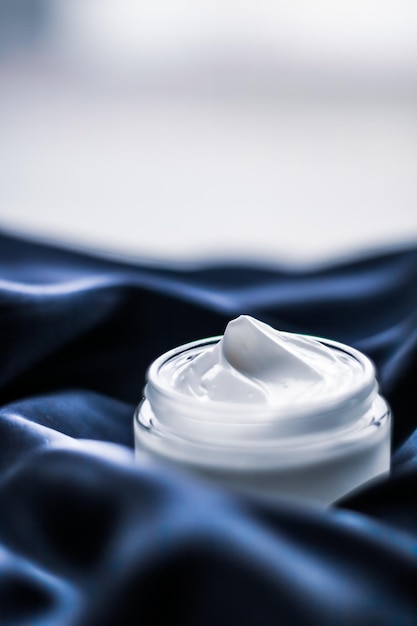 Pot de crème pour le visage de luxe sur une soie bleu foncé