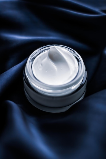 Pot de crème pour le visage de luxe sur une soie bleu foncé