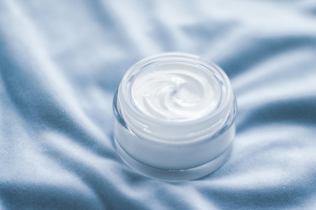 Pot de crème pour le visage de luxe sur une soie bleue