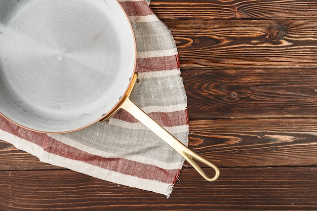 Pot en cuivre avec une nappe de cheker sur une table en bois