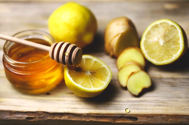 Photo pot avec du miel sur la table avec du gingembre et des citrons à côté