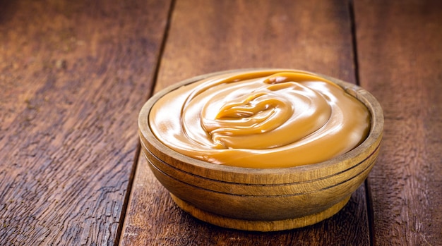 Pot de dulce de leche ou caramel fait maison sur le fond en bois rustique, doux brésilien typique