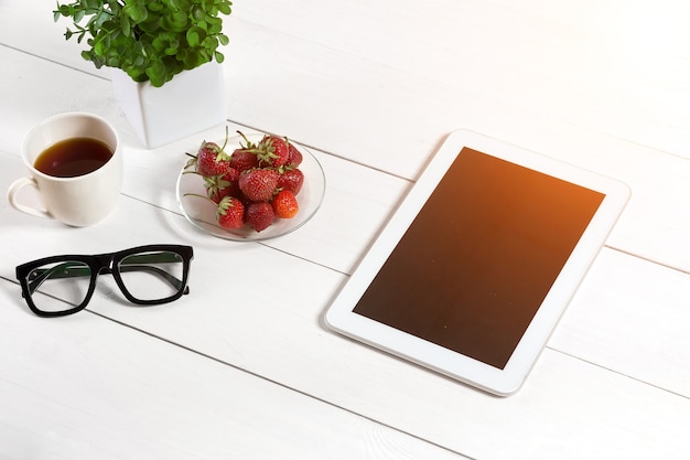 Pot de fleurs, verres, tablette sur le bureau blanc. Fond blanc. Vue de dessus. Espace de copie. Éclat de soleil