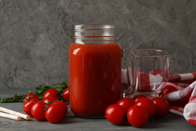 Pot de jus de tomate, tomates et torchon sur fond de bois