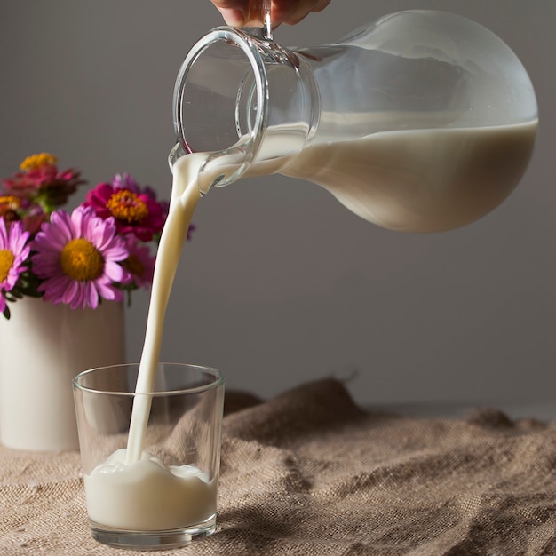 Un pot de lait et un verre dans un style rustique sur une nappe en toile de jute