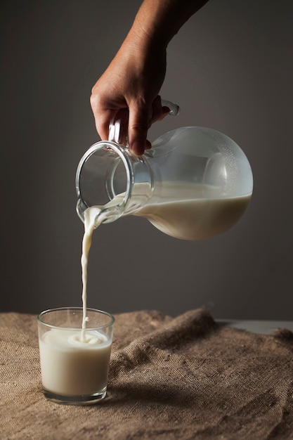 Un pot de lait et un verre dans un style rustique sur une nappe en toile de jute