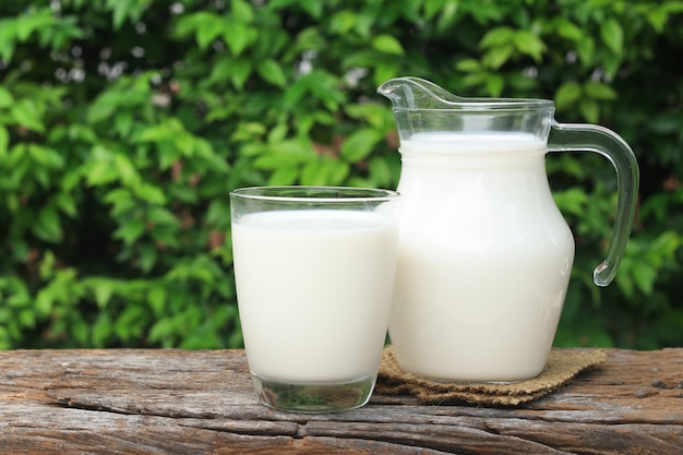 Un pot de lait et un verre de lait sur une table en bois.