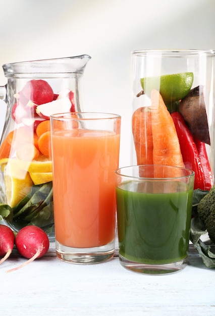 Pot de légumes coupés et verre de jus de légumes frais avec des légumes sur une table en bois