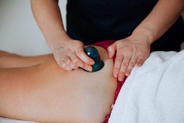 Pot de massage corporel sur la jambe de la personne Massothérapeute faisant un massage avec un pot de massage sous vide