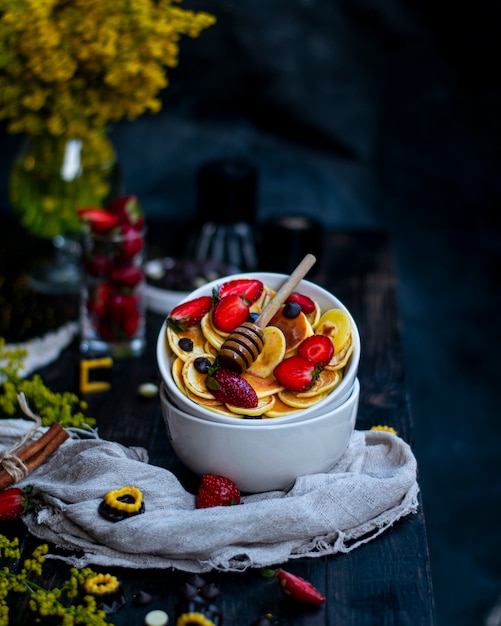 Pot de miel sur des bols de fruits