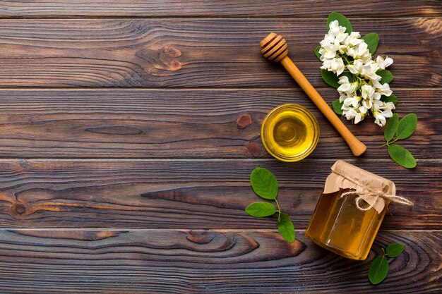 Pot de miel avec des fleurs d'acacia et des feuilles de miel frais vue de dessus à plat